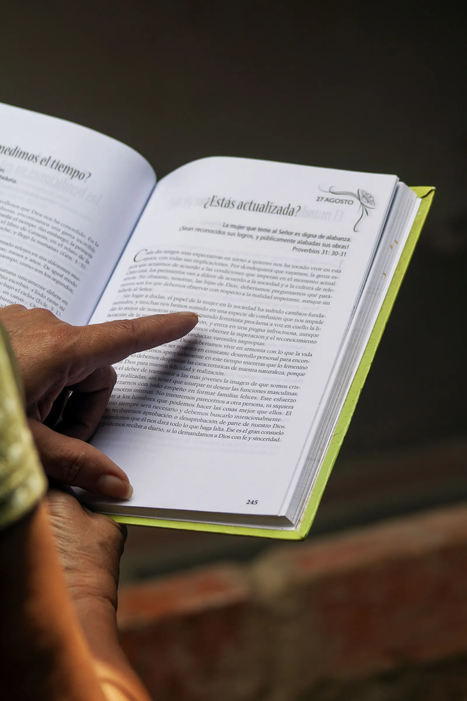 Une personne feuillette un kiosque à journaux et livres d'occasion en plein air.