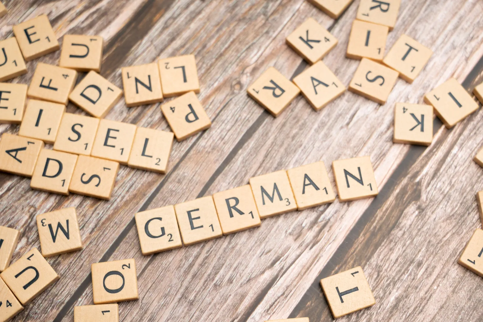 Des lettres de Scrabble en bois formant le mot GERMAN sur une table en bois.