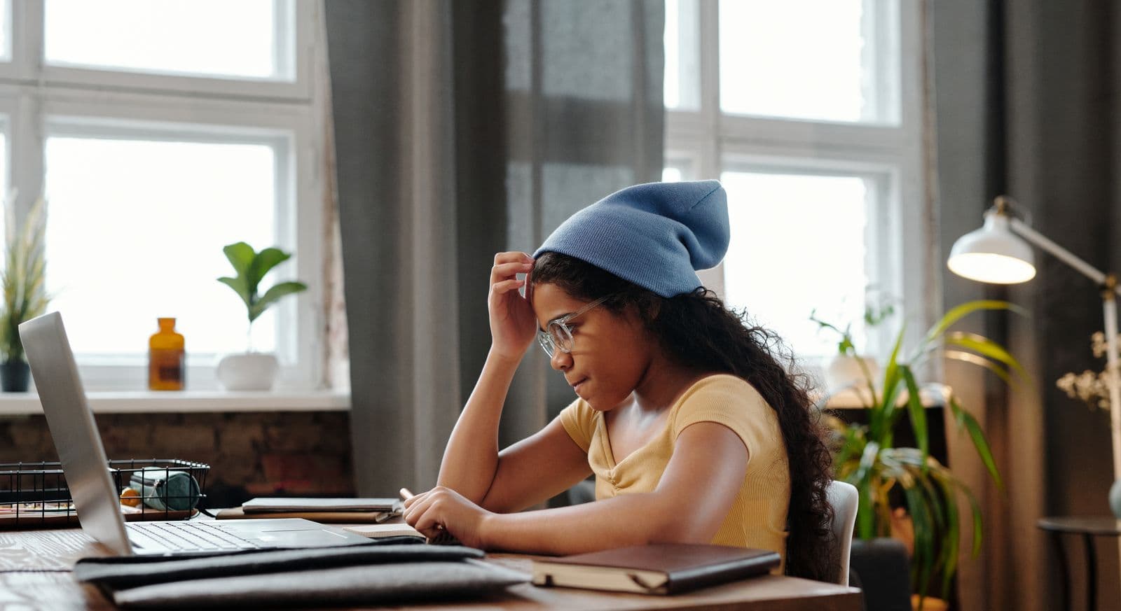 Personne lisant sur un ordinateur portable à un bureau, concentrée sur un texte