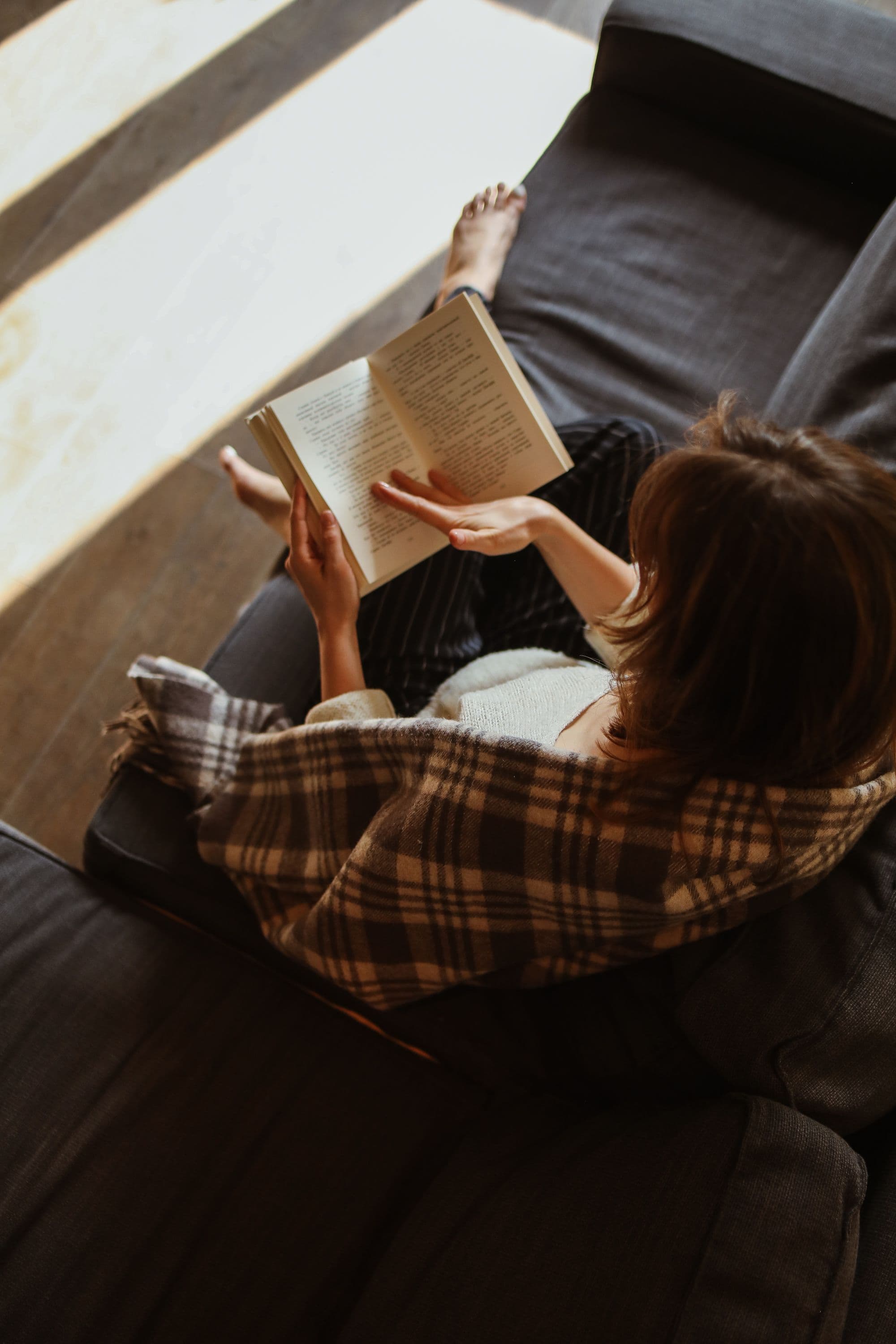 Personne lisant tranquillement un livre, tasse de café à côté