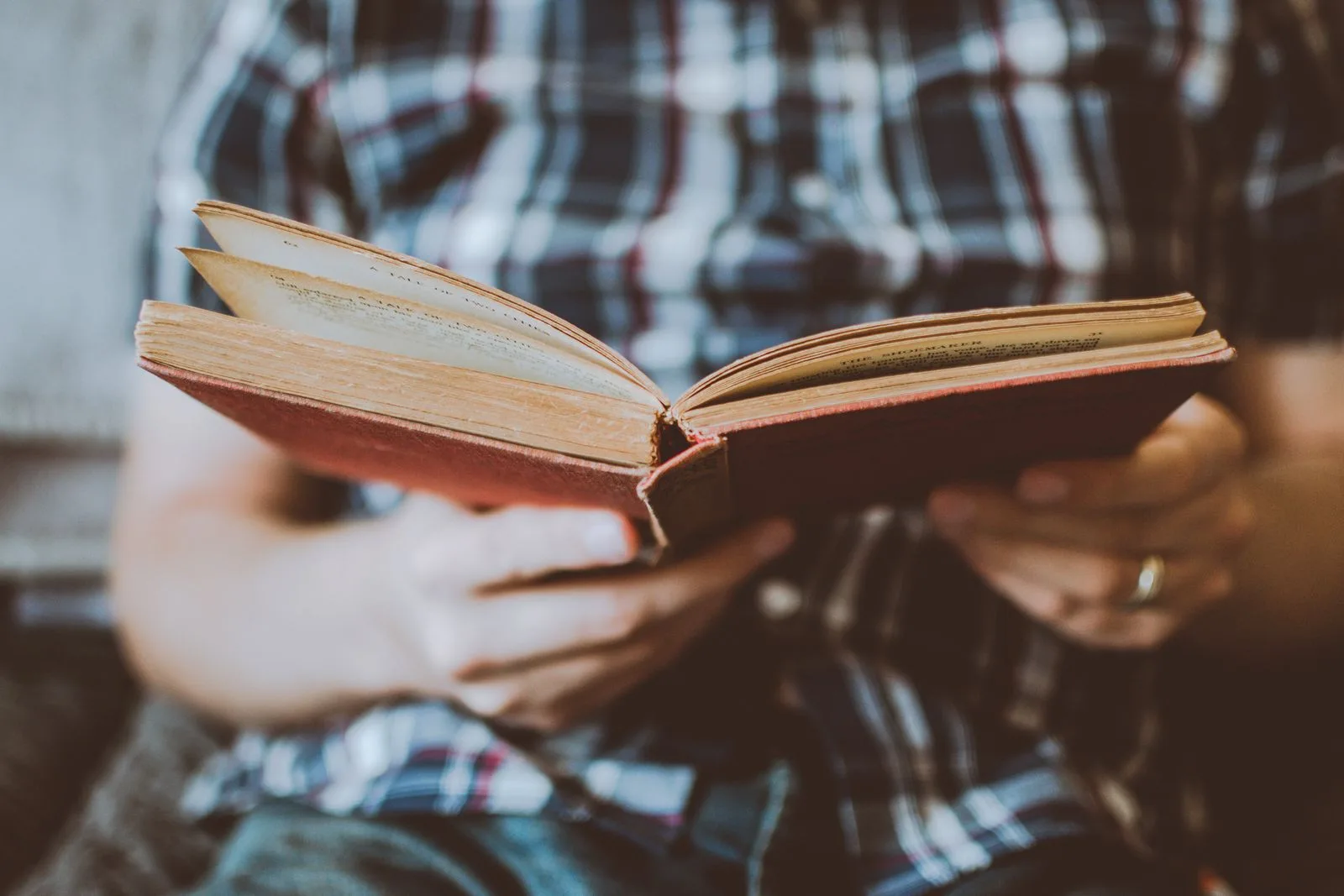 Des mains tiennent un livre ancien ouvert, lecture concentrée et studieuse.